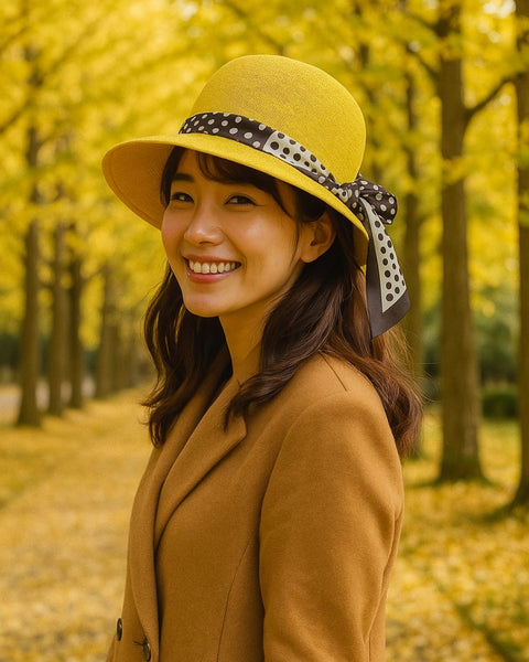 Woman wearing a yellow hat with a polka dot ribbon in an autumn setting