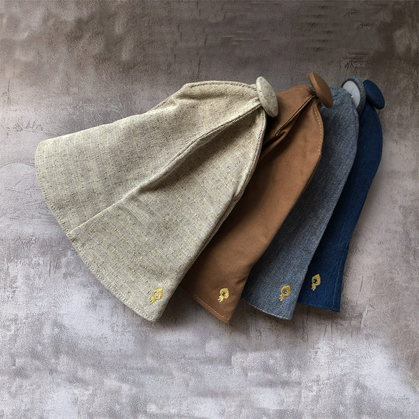 Set of four fabric bags in beige, brown, blue, and gray on a textured surface.